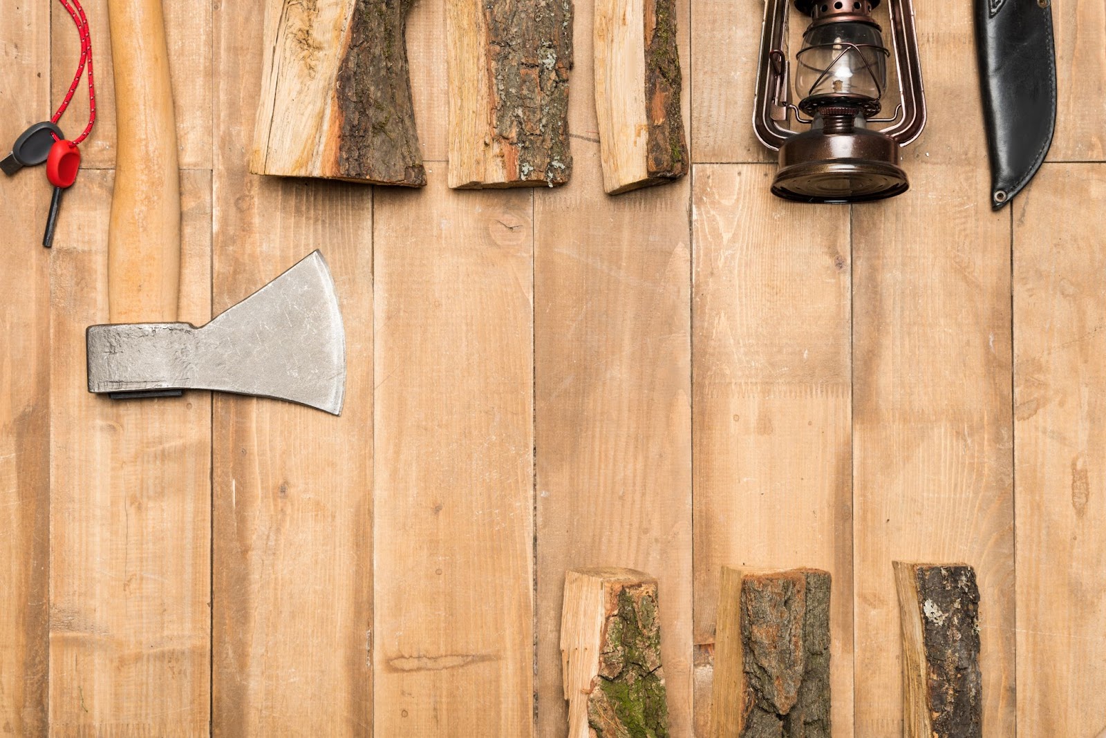  An axe next to pieces of wood, a lantern, and a knife. 