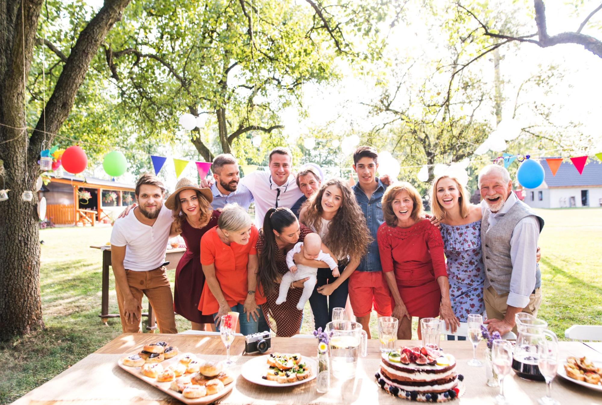 A family celebrating a birthday in a garden looks at the camera for a photo.