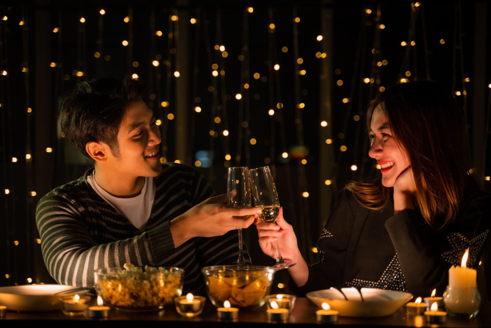  A couple enjoying a date night outdoors surrounded by lights with candles on the table. 