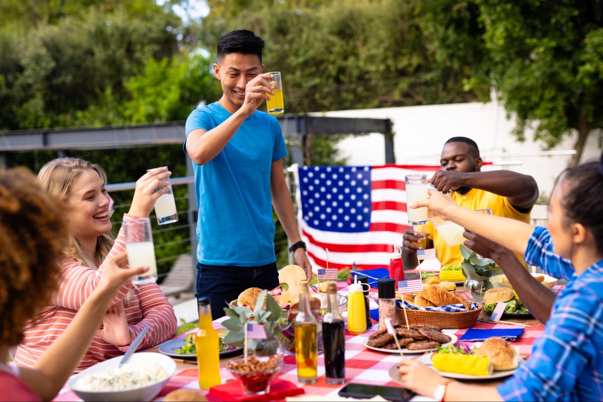 A group of friends cheered with drinks and food, celebrating Independence Day.