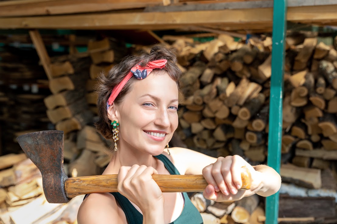 A woman wearing a red bandana holds a rusty axe.