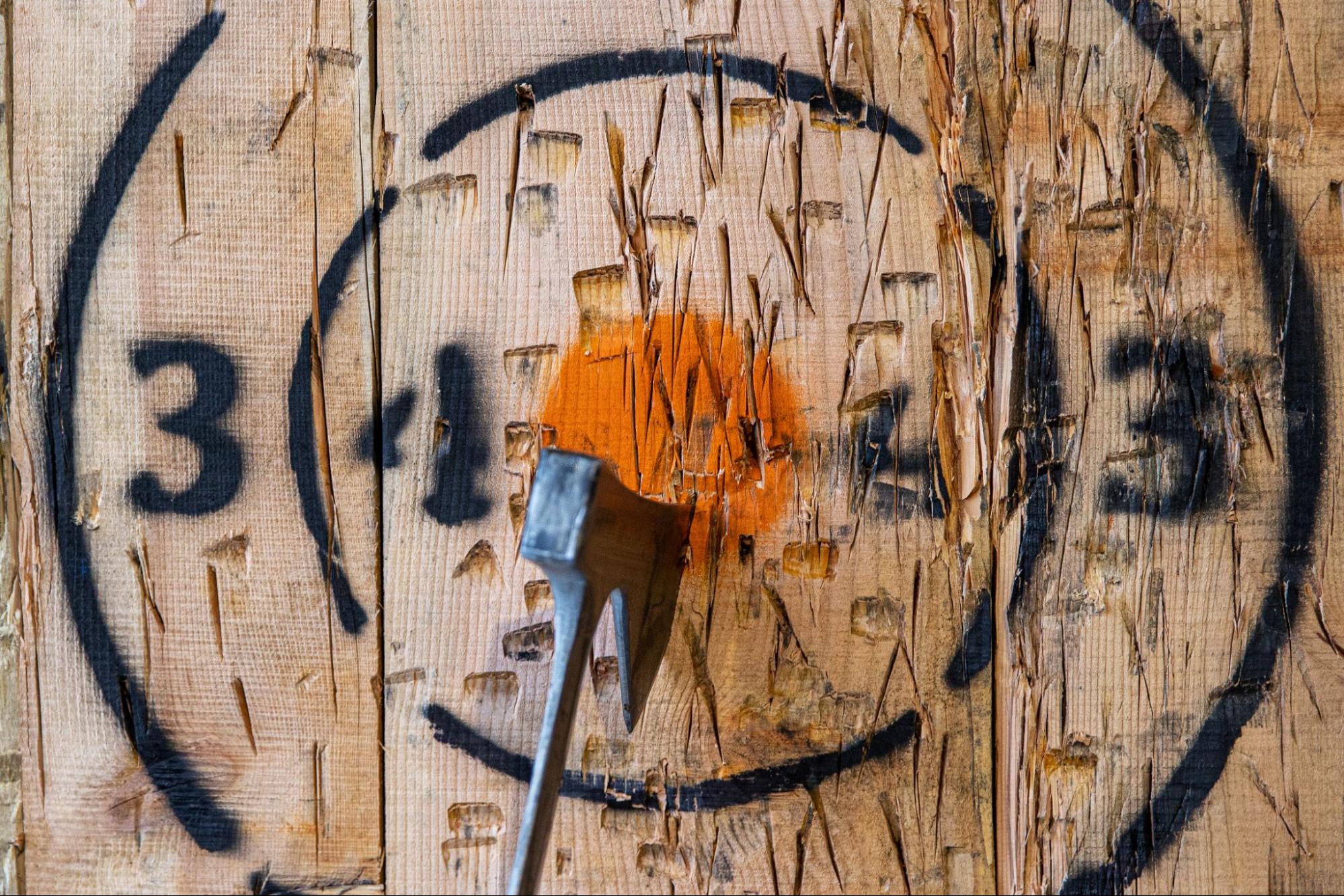 An axe thrown into the center bullseye on a wooden target.