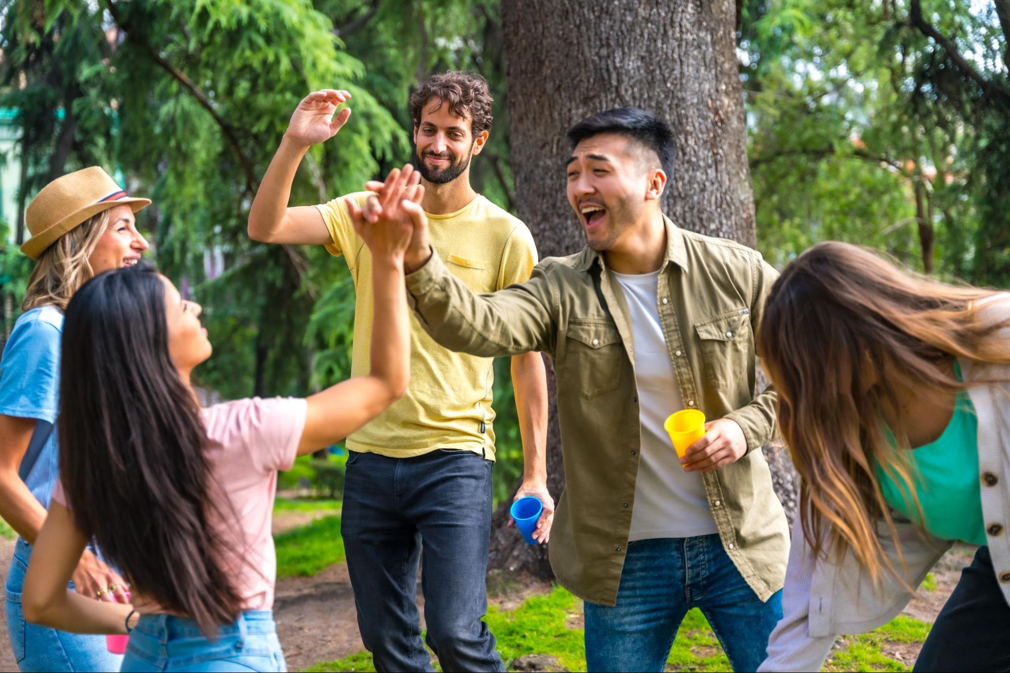 Friends hanging out outside and exchanging high fives. 