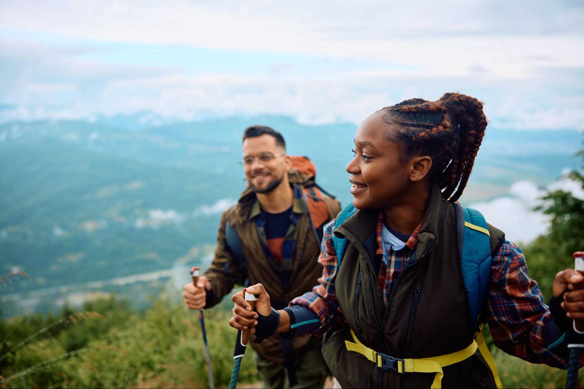 Man and a woman smiling and hiking in the mountains. 