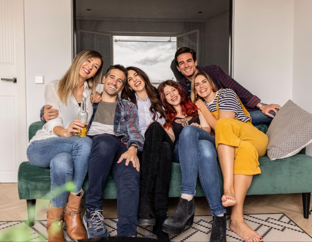 Group of friends sitting on a couch and smiling.