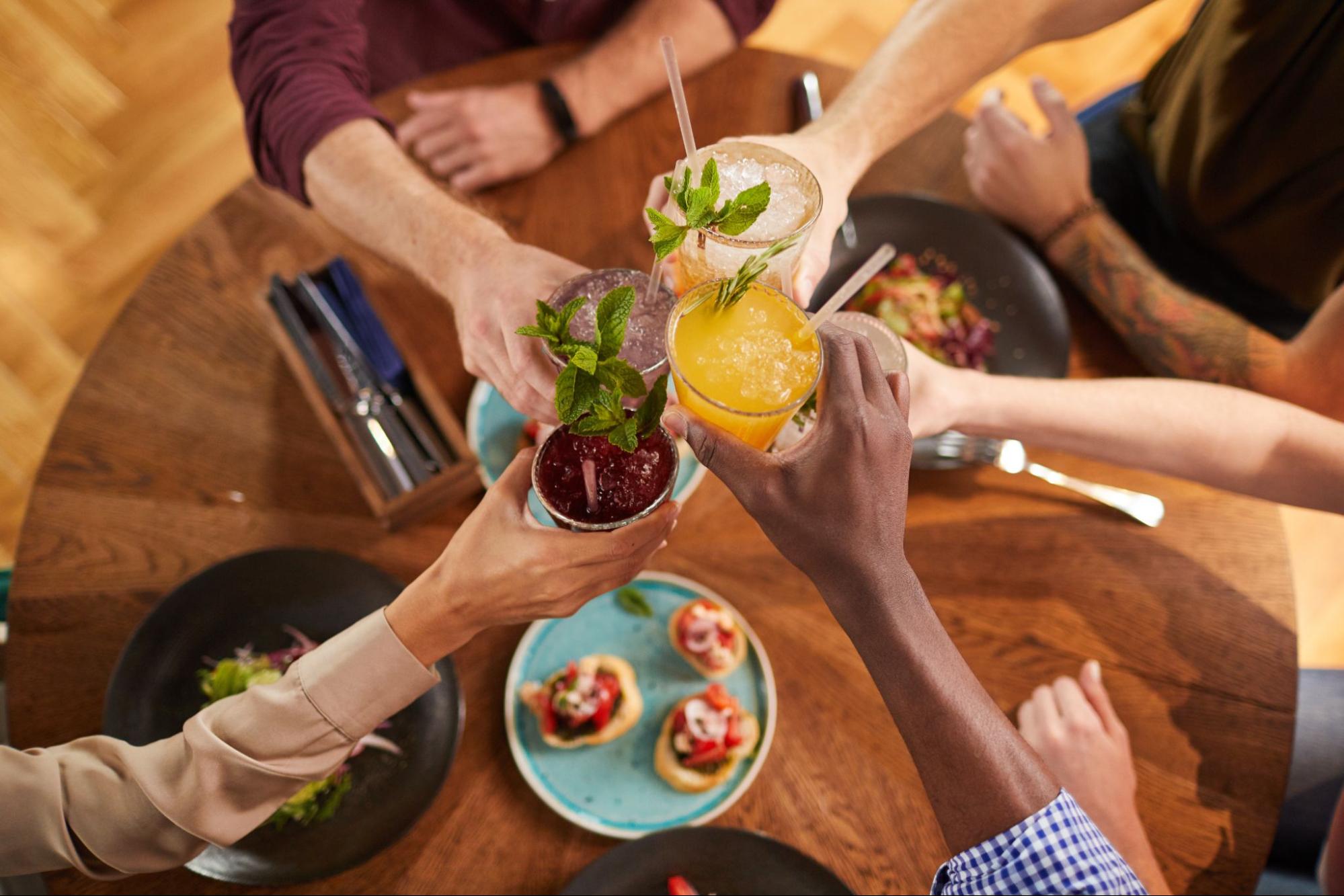 Four people toasting with drinks around a table. 