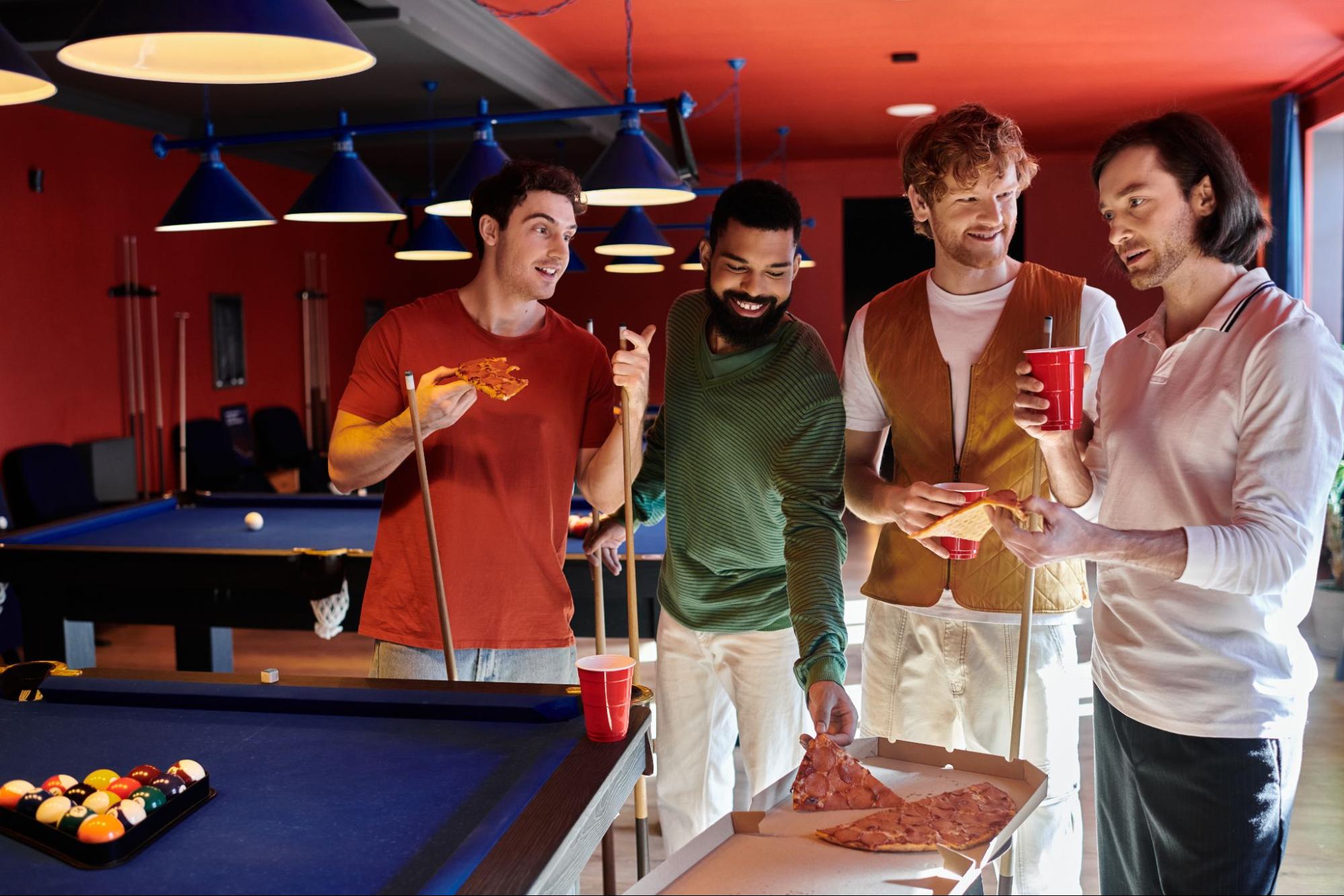 Men eating pizza around a pool table.