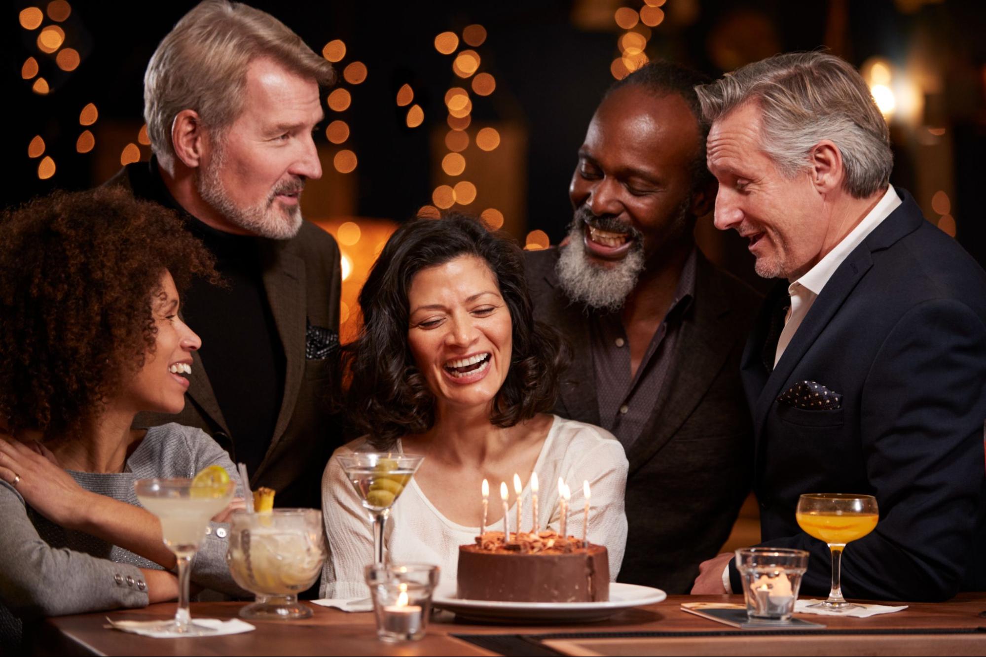 Group of older friends around a cake.