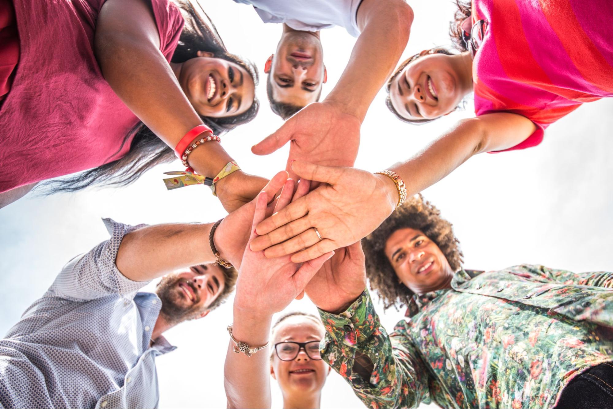 A group of co-workers putting hands on top of each other before entering a friendly competition.