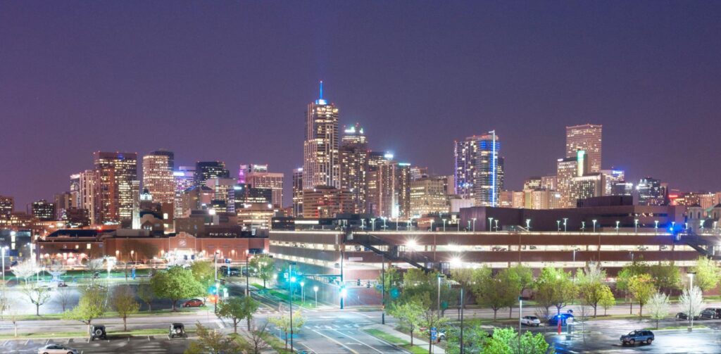 Downtown Denver, Colorado's illuminated nighttime skyline showcases the cityscape with glowing city lights and high-rise buildings.