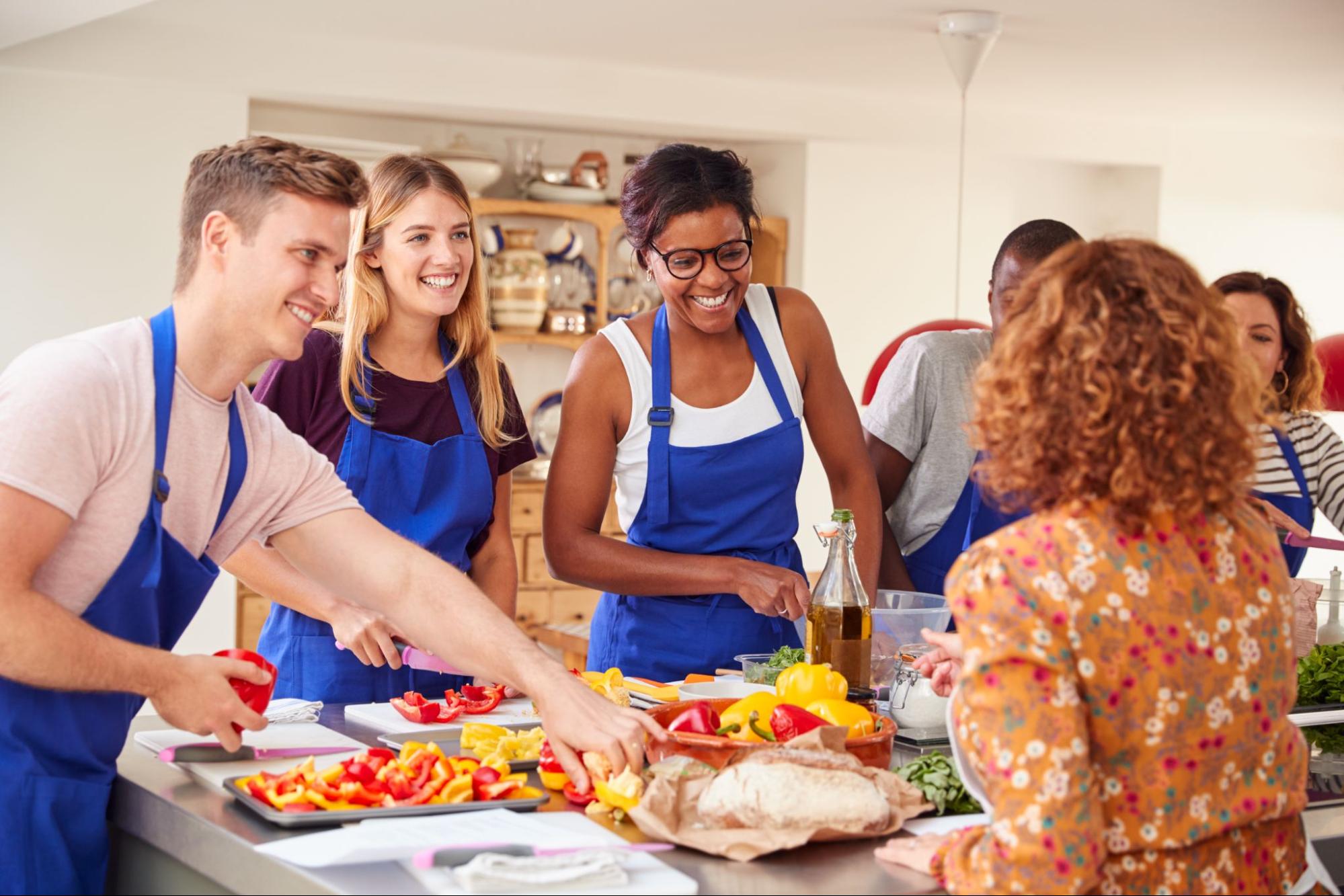 Group of people wearing aprons taking a cooking class.