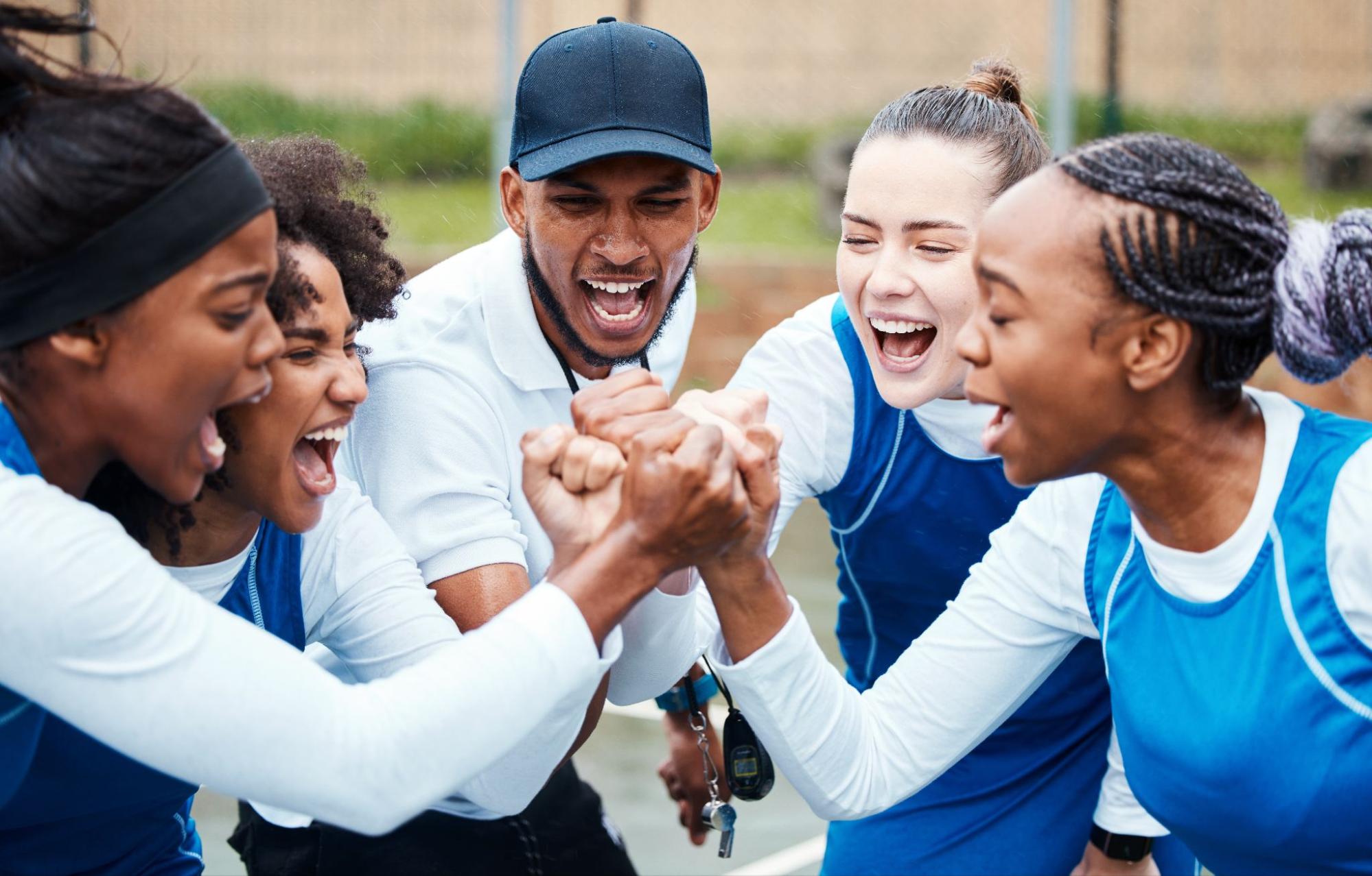 A close-up of teammates’ fists joined together to display unity and motivation during a team sports play.